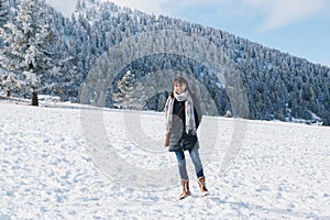 Young smiling caucasian woman at snowy slope enjoying winter holidays at ski resort with splendid snow-covered mountains