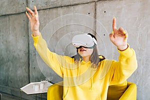 Young smiling caucasian woman using VR headset, gesturing and looking up in virtual reality