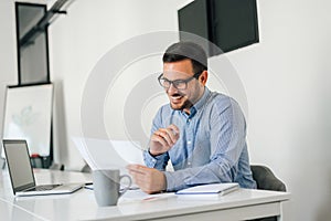 Young smiling cheerful confident businessman checking working plan and schedule or timetable in office copy space screen empty