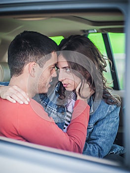 Young smiling and cheerful couple in love, sitting in the back seat