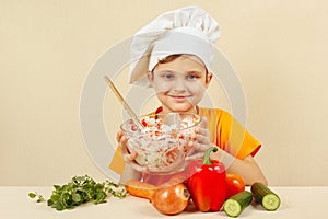 Young smiling chef prepared salad of fresh vegetables