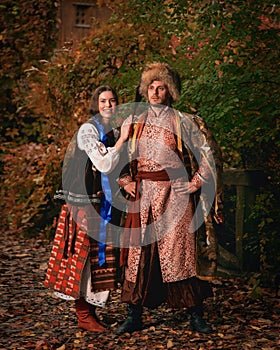 Young smiling couple dressed traditional ukrainian clothing. Cossack man and woman in embroidered costumes outdoors