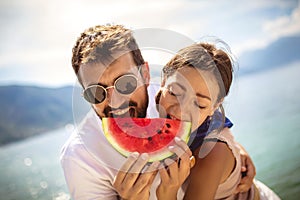 Smiling couple eating watermelon on the beach having fun