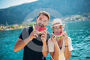 Smiling couple eating watermelon on the beach having fun