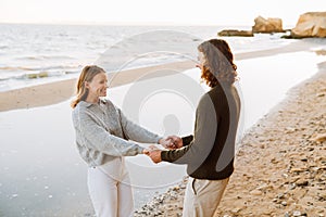 Young smiling couple holding hands while spending time together at beach