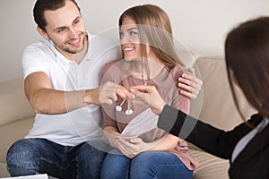 Young smiling couple owners getting keys to own house apartment