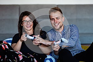 Young smiling couple playing videogames at home.