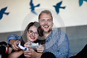 Young smiling couple playing videogames at home.