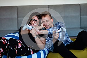 Young smiling couple playing videogames at home.