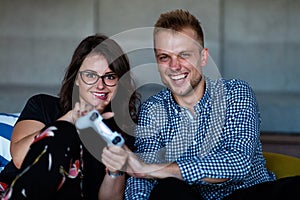 Young smiling couple playing videogames at home.