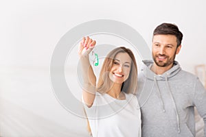 Young smiling couple showing keys of new home