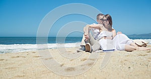 Young smiling couple sitting on the beach