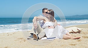 Young smiling couple sitting on the beach