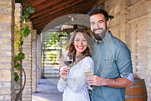 Young smiling couple tasting wine at winery outdoors