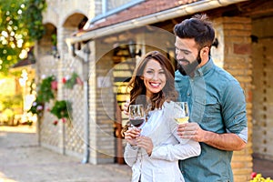 Young smiling couple tasting wine at winery outdoors