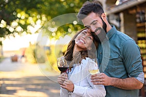 Young smiling couple tasting wine at winery outdoors