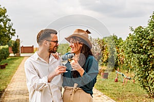 Young smiling couple tasting wine at winery vineyard