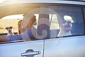 Young smiling couple and their two dogs traveling by car