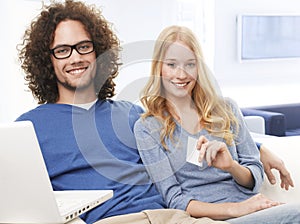 Young smiling couple using credit card and shopping on internet