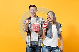 Young smiling couple woman and man watching movie film on date holding bucket of popcorn plastic cup of soda or cola