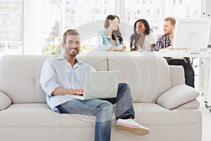 Young smiling designer working on his laptop on the couch