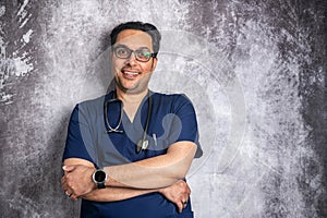 young smiling doctor in glasses with a stethoscope near a gray wall. Space for text