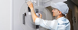 Young smiling electrician doing his work, electrical panel