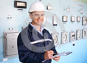 Young smiling engineer taking notes at control room