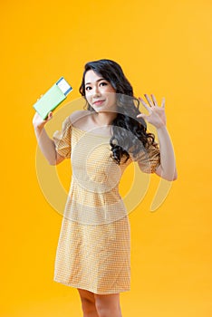 Young smiling excited woman student holding passport boarding pass ticket isolated on yellow background