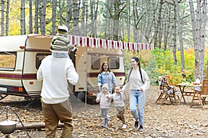 Young smiling family while hugging near house on wheels outdoors