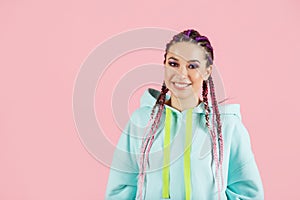 Young smiling fashionable woman with braids kanekalon isolated on pink background