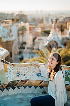 Young smiling female tourist spending vacation in Barcelona,Catalonia,Spain.Traveling to Europe,visiting Parc Guell.Panoramic view