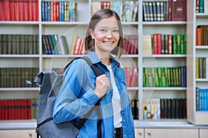 Female university student with backpack, inside library of educational building