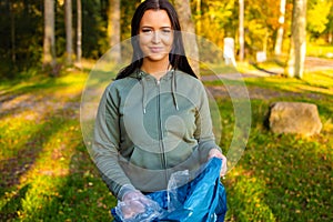 Young smiling female volunteer holding garbage bag at park