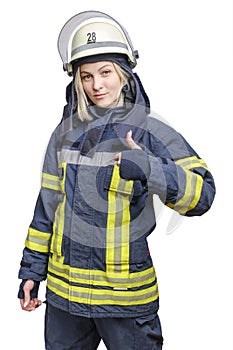 A young smiling fireman girl in a helmet and wearing fireproof uniform, stands and make gesture ok.