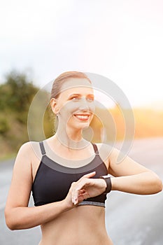 Young smiling fitness woman using her smart watch