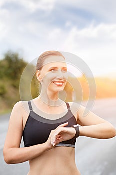 Young smiling fitness woman using her smart watch