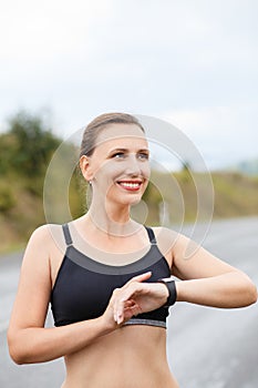 Young smiling fitness woman using her smart watch