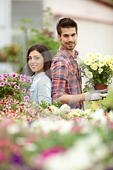 Young smiling florists man and woman working in the greenhouse