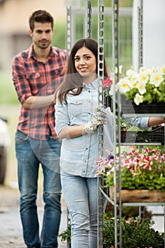 Young smiling florists man and woman working in the greenhouse