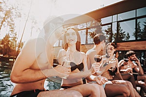 Young Smiling Friends Drinking Wine at Poolside