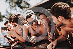 Young Smiling Friends using Smartphone at Poolside