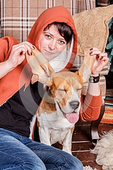 Young smiling girl with funny and silly beagle dog who shows the tongue with closed pleased eyes