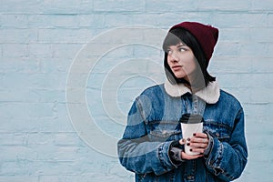 Young smiling girl hipster hot drink in hand, on a light background
