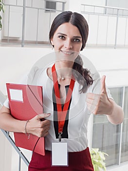 Young Smiling Girl Made Successful Work Shows Gesture Big Thumb Up. Beautiful Smiling Businesswoman Standing Against White Offices