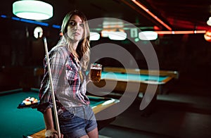 Young smiling girl playing billiard in club