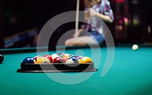 Young smiling girl playing billiard in club