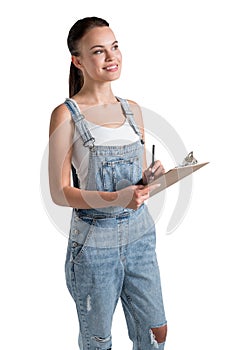 Young smiling girl in white T-shirt and a denim overalls holding a planner and dreaming about to do list of upcoming week.