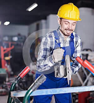 Young smiling guy using angle grinder for construction