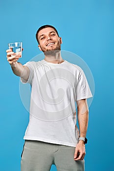 Young smiling handsome man offering a glass of water
